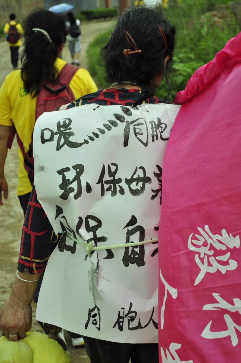 集聚萤火·与爱同行，2011徒步湘江毅行：一位阿姨写着醒目的提示语背在身上！